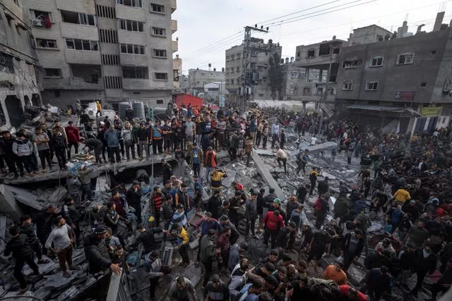 Palestinians search for bodies and survivors in the rubble of a residential building destroyed in an Israeli air strike, in Rafah