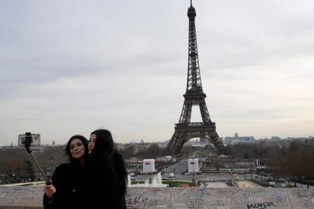 Tourists take a selfie in front of the Eiffel Tower in Paris 