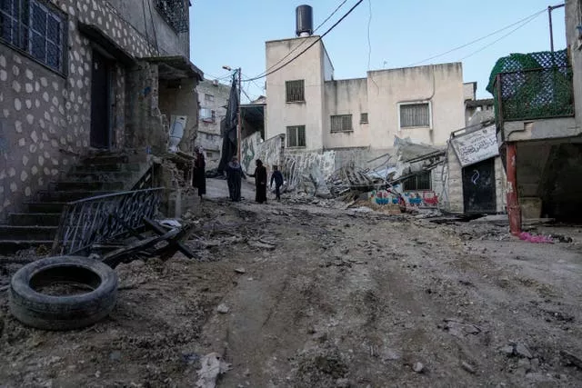 Palestinians walk through the aftermath of the Israeli military raid on Nur Shams refugee camp in the West Bank