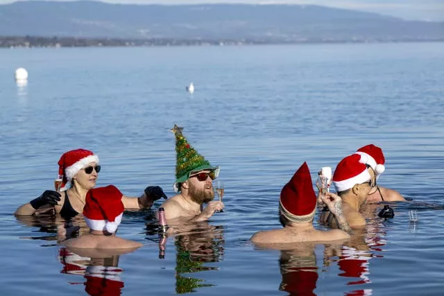 People drink as they swim with Santa hats in Lake Leman at Bains des Paquis on Christmas Eve, in Geneva, Switzerland (Martial Trezzini/AP)