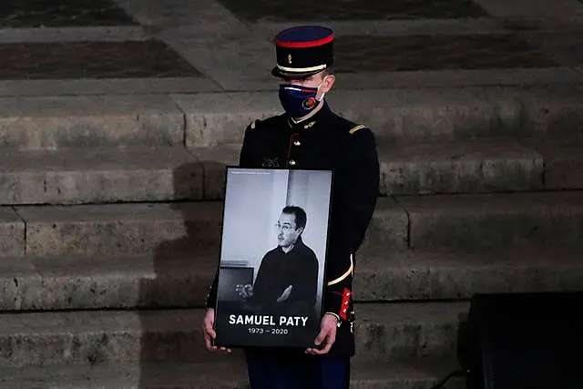 A Republican Guard holds a portrait of Samuel Paty