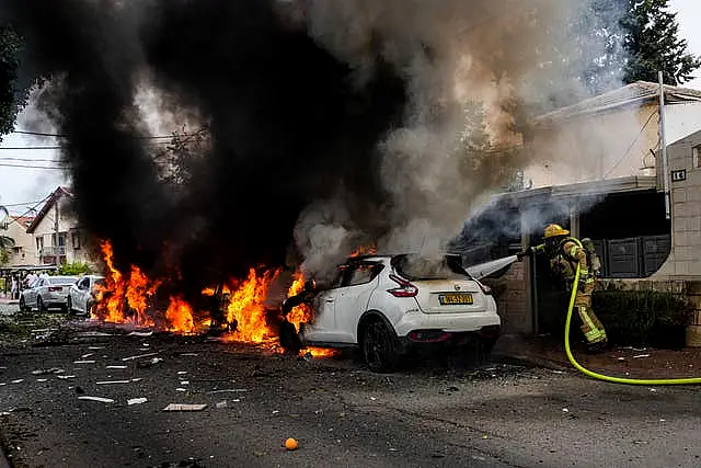 Israeli firefighters extinguish fire at a site struck by a rocket fired from the Gaza Strip in Ashkelon, southern Israel on Monday