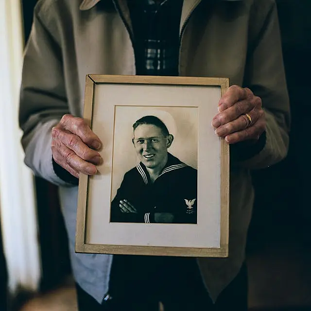 Warren Upton holds a picture of himself as a young serviceman