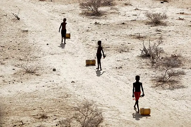 Young boys pull containers of water as they return to their huts from a well in the village of Ntabasi village amid a drought in Samburu East, Kenya, in October 2022