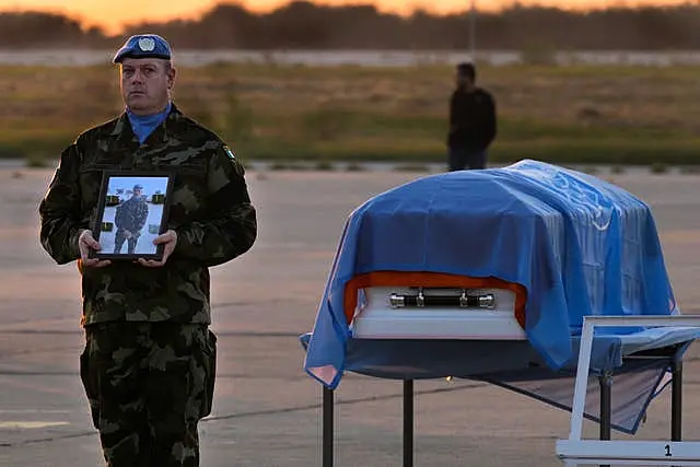 An Irish UN peacekeeper stands next to the coffin of his comrade Sean Rooney