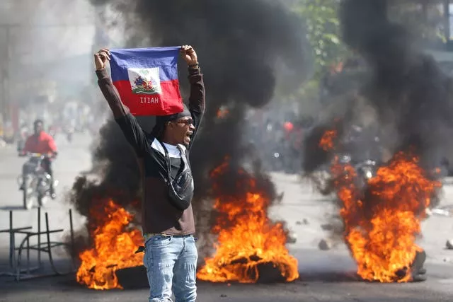 A demonstrator holds up a Haitian flag during protests demanding the resignation of Prime Minister Ariel Henry