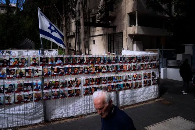 People pass by a fence with photographs of Israelis who are being held hostage in the Gaza Strip 