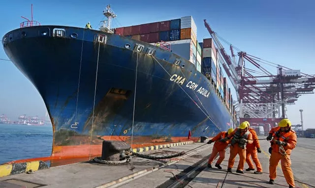 Trabalhadores atracam um navio porta-contêineres em um porto na China 
