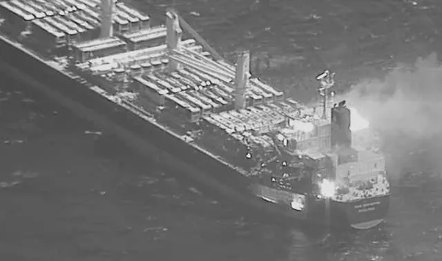 A black-and-white image shows a fire aboard the bulk carrier