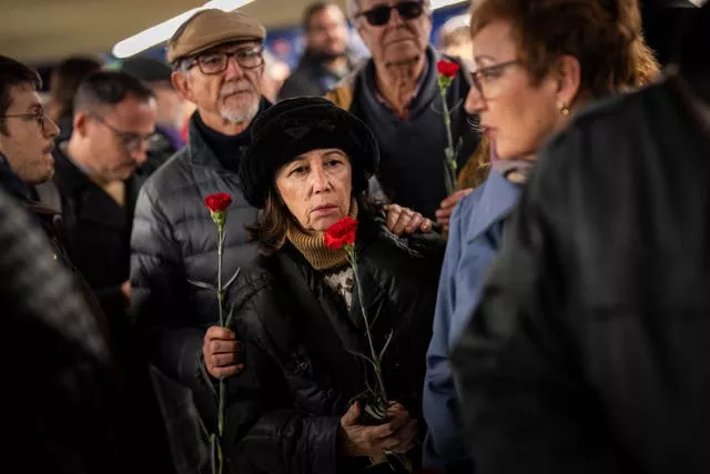 Pessoas fazem fila para depositar flores em um memorial