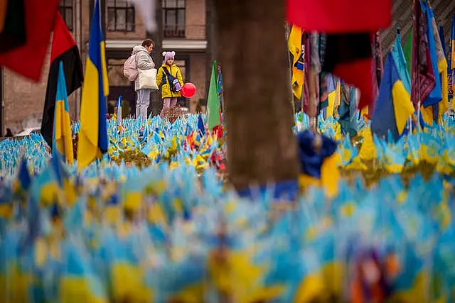 A child holds a balloon while looking at a memorial for soldiers who perished in the war in Kyiv, Ukraine