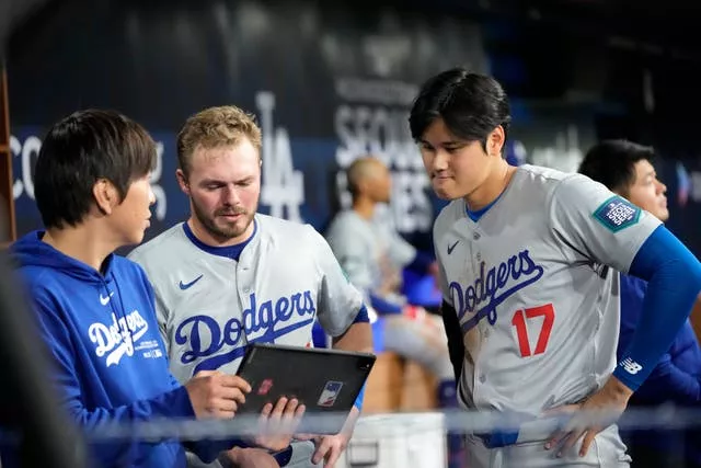 Gavin Lux, do Los Angeles Dodgers, ao centro, e Shohei Ohtani, à direita, conversam com o intérprete Ippei Mizuhara durante o primeiro turno de um jogo de beisebol do dia de abertura contra o San Diego Padres no Gocheok Sky Dome em Seul, Coreia do Sul, em 20 de março