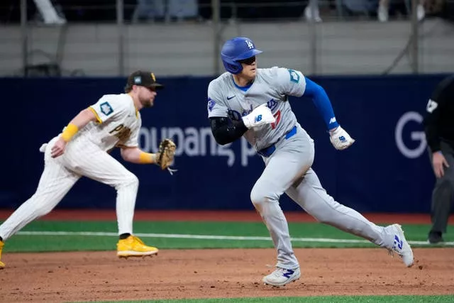 O rebatedor designado do Los Angeles Dodgers, Shohei Ohtani, à direita, cabeceia para o segundo lugar em uma bola rebatida por Freddie Freeman durante a oitava entrada de um jogo de beisebol do dia de abertura contra o San Diego Padres no Gocheok Sky Dome em Seul, Coreia do Sul, em 20 de março.