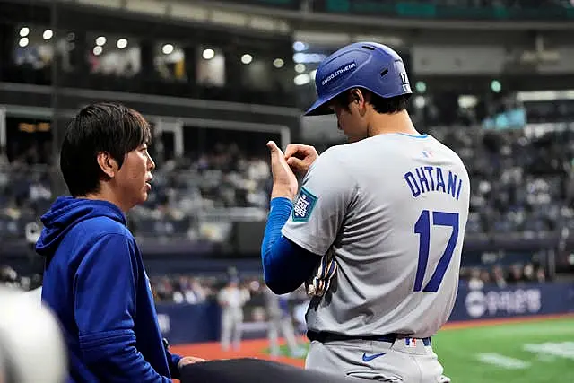 O rebatedor designado do Los Angeles Dodgers, Shohei Ohtani, à direita, fala com seu intérprete Ippei Mizuhara durante o quinto turno de um jogo de beisebol do dia de abertura contra o San Diego Padres no Gocheok Sky Dome em Seul, Coreia do Sul, em 20 de março