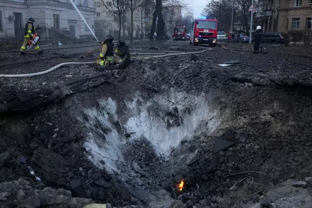 Bombeiros trabalham perto de uma cratera após um ataque russo em Kiev, Ucrânia 