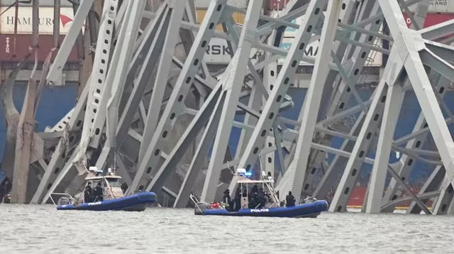 Des bateaux de police travaillent autour d'un cargo coincé sous une partie de la structure du pont Francis Scott Key à Baltimore