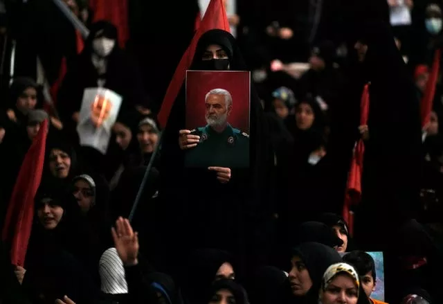 A woman holds up a poster of Qassem Soleimani during a commemoration in Tehran