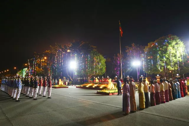 Membros de uma guarda de honra e representantes de raças étnicas nacionais saúdam a sua bandeira nacional 