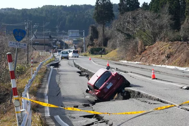 A car is trapped at a partially collapsed road caused by a powerful earthquake near Anamizu Town, Ishikawa prefecture
