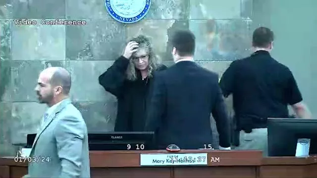 Judge Mary Kay Holthus holds her head after the attack