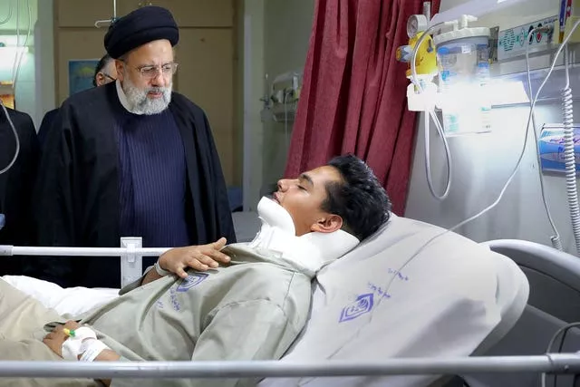 Iranian President Ebrahim Raisi visits a man hurt in the attack
