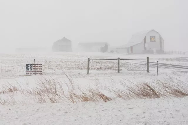 An American flag is mounted on a farm fence along US Highway 20 during a blizzard near Galva, Iowa