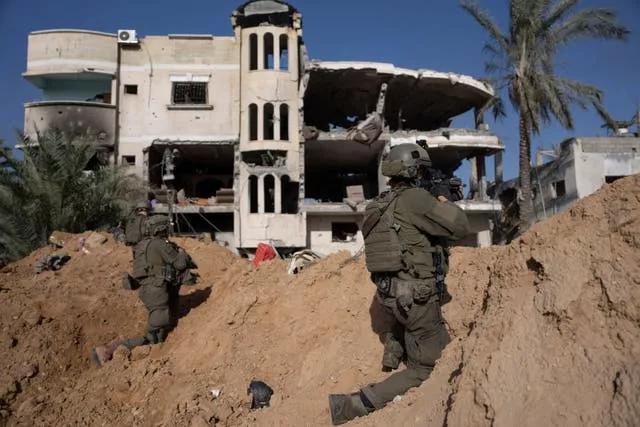 Soldados israelenses posicionam-se próximos a um prédio destruído durante uma operação terrestre em Khan Younis, Faixa de Gaza, na quarta-feira