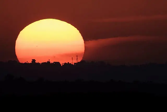 The sun sets behind buildings in the Gaza Strip on Tuesday