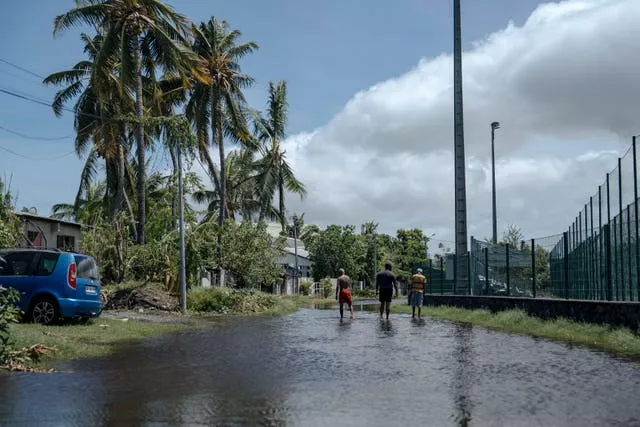 Men walk on a submerged street in the town of Saint-Paul, on the French Indian Ocean island of Reunion