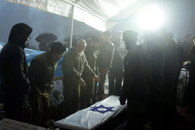 Israeli soldiers lower the flag-draped casket of reservist Ariel Mordechay Wollfstal during his funeral at a cemetery in the West Bank settlement of Kfar Etzion on Tuesday