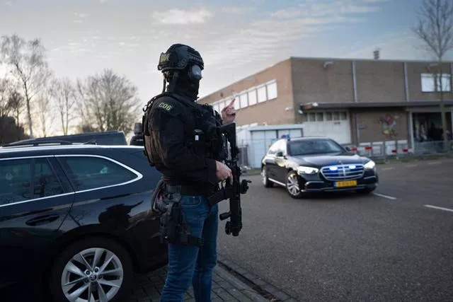 Masked and armed Dutch police guard a transport of some of the suspects who arrived at the high security court building where the trial opened in Amsterdam 