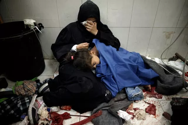 A Palestinian woman cries as she sits next to her girl wounded in the Israeli bombardment of the Gaza Strip while receiving treatment at the Nasser hospital in Khan Younis, Southern Gaza Strip, on Monday