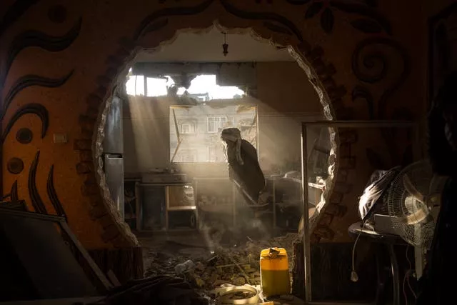 Palestinos olham para a casa danificada de seu vizinho após um ataque aéreo israelense em Rafah