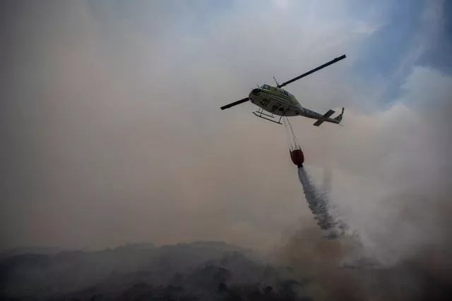 A helicopter drops water as firefighters battle wildfires in Pringle Bay on Tuesday