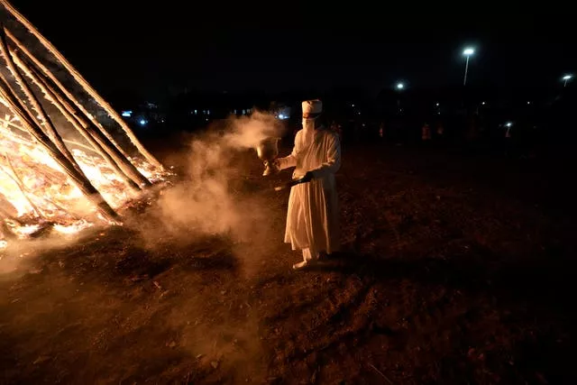 A Zoroastrian priest walks near a giant bonfire