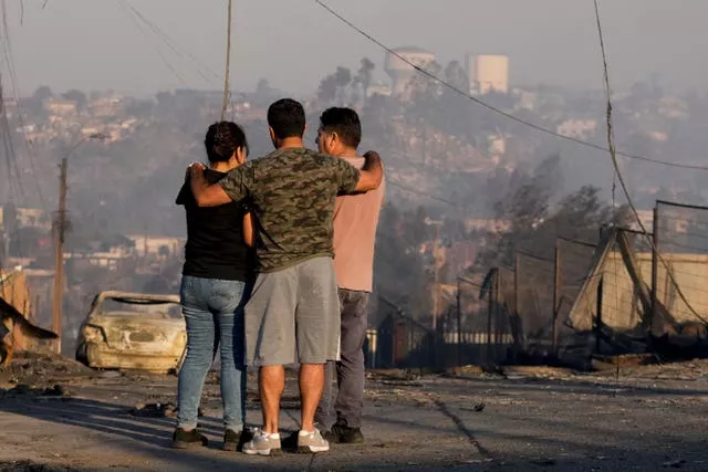 Moradores observam casas queimadas e outros destroços depois que um incêndio florestal atingiu seu bairro em Vina del Mar, Chile