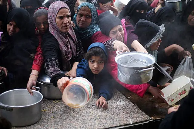 Palestinians line up for free food distribution during the ongoing Israeli air and ground offensive in Khan Younis, Gaza Strip