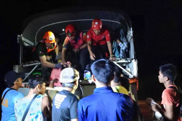 Volunteers assist residents being evacuated to safer grounds following a landslide at their village at Maco, Davao de Oro province, south Philippines 