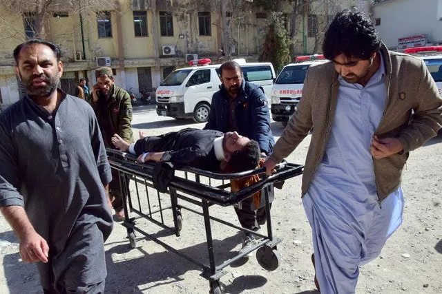 Trabalhadores e voluntários transportam uma vítima ferida da explosão de bomba no distrito de Pashin ao chegar a um hospital em Quetta, Paquistão