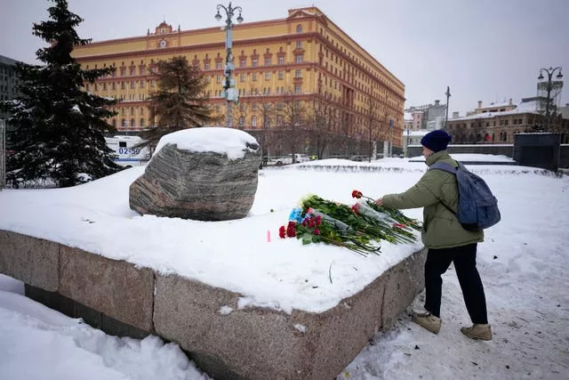 A woman lays flowers paying the last respects to Alexei Navalny at the monument where the first camp of the Gulag political prison system was established, with the historical the Federal Security Service (FSB, Soviet KGB successor) building in the background, in Moscow, Russia 