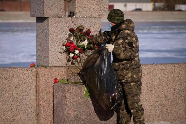 A municipal worker, on orders from the authorities, removes flowers brought by people to pay respect to Alexei Navalny from the Memorial to Victims of Political Repression in St Petersburg, Russia