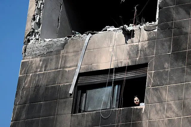 A girl looks out from a window of a residential building after a reported Israeli attack on Syria (Omar Sanadiki/AP)