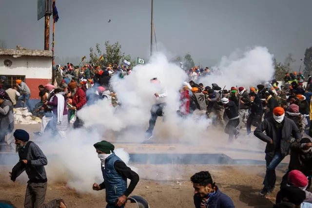 Agricultores em protesto fogem de bombas de gás lacrimogêneo usadas pela polícia perto da fronteira de Shambhu, Índia (Altaf Qadri/AP)