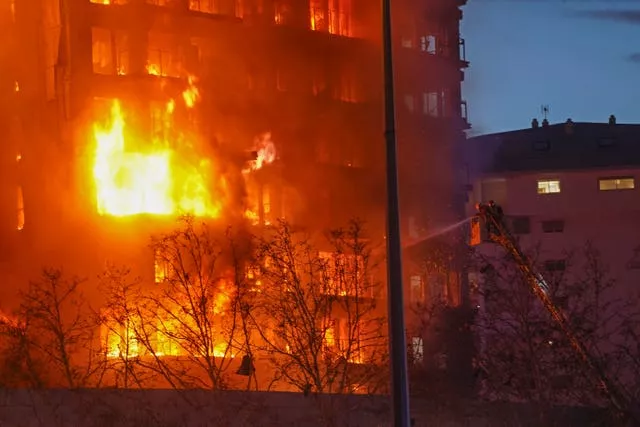 Firefighters spray water on a housing block as it burns in Valencia, Spain