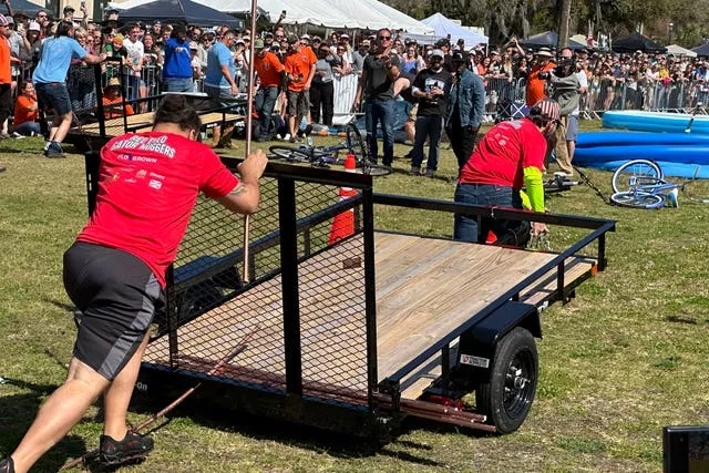 Competitors push a trailer during a relay race at the Florida Man Games