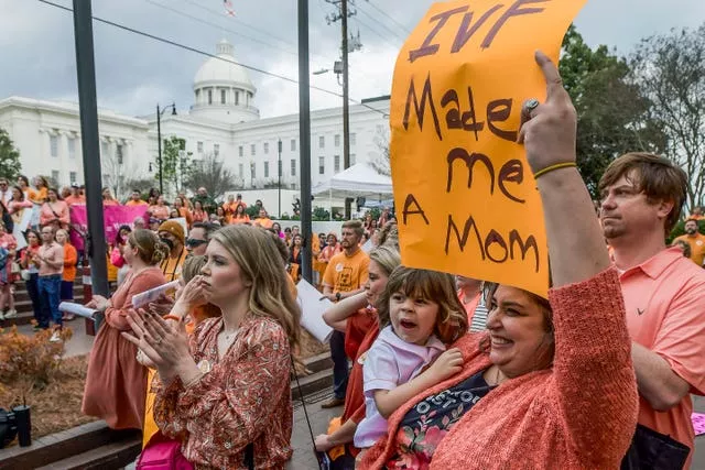 A woman holds a sign and her son as hundreds gathered for a protest rally for in vitro fertilization legislation last month 