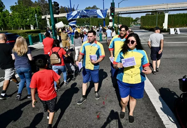 Pixar Pier attractions operators Ruth Lopez, right, and Vinny Ramano, join other Disney union members as they pass out buttons and ask visitors to sign a petition 