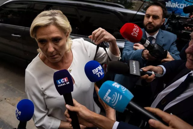Marine Le Pen speaks into a bank of microphones 