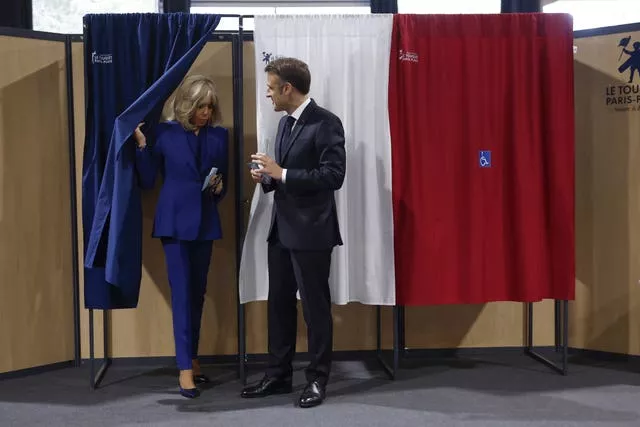 Emmanuel Macron and his wife Brigitte Macron leave a voting booth