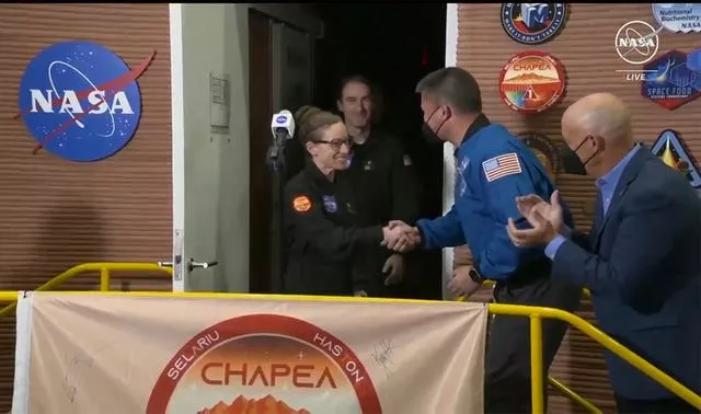 Kelly Haston, centre, shakes hands with Nasa deputy director flight missions Kjell Lindgren, second right, as other crew members emerge from their habitat